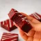 Stack of fudgy red velvet brownie squares with a crackly top, dusted with powdered sugar and drizzled with white chocolate — a cozy autumn treat.