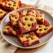 Close-up of a warm red-velvet brookie with a fudgy red center and chewy chocolate-chip cookie layer, sliced and sprinkled with flaky sea salt.