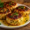Sliced garlic Parmesan chicken meatloaf on a plate, garnished with chopped parsley, served alongside mashed potatoes and roasted green beans.