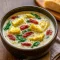 Creamy lemony artichoke soup in a bowl, garnished with parsley and a lemon wedge, served with crusty bread on the side.