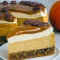 Slice of pecan pie pumpkin cheesecake on a white plate, drizzled with caramel and topped with candied pecans, fork at the side.