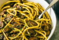 Spaghetti tossed with sautéed mushrooms, garlic, chili flakes, parsley and grated Parmesan in a shallow bowl.