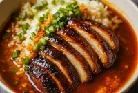 Bowl of tender Soy Chicken served over fluffy rice in a garlic ginger broth, topped with fresh herbs – the perfect cozy comfort meal for lovers of Asian Dishes and quick Chicken Dinner Recipes.