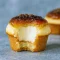 Close-up of a vanilla bean crème brûlée cupcake with a glossy, caramelized sugar top and creamy filling, photographed on a rustic plate.