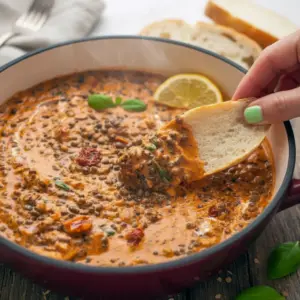 Photo of a bowl of creamy sundried-tomato lentils garnished with basil and grated cheese; ideas for What To Serve With Lentils, the Best Way To Cook Lentils, tips for Cooking With Beans And Lentils, and simple Lunches With Lentils.