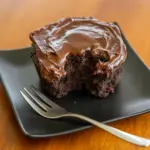 Fudgy chocolate mug cake in a white mug, spoon scooping a warm, gooey center (topped with a small dollop of whipped cream).