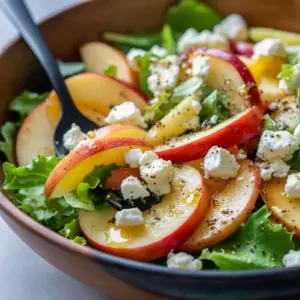 Close-up of a Honeycrisp apple and feta salad — arugula, thin apple slices, pomegranate seeds, candied pecans and crispy prosciutto, all drizzled with apple-cider vinaigrette, Fresh Salad Recipes.