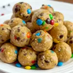 The Best Energy Balls stacked on parchment with visible mini chocolate chips and colorful M&Ms — a tempting Monster Cookie snack.