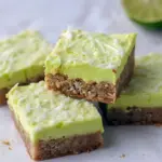 Squares of lime-frosted coconut bars with shredded coconut and a white chocolate drizzle on a festive serving board, Starbucks Bars.