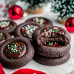 Close-up of chocolate thumbprint cookies with glossy ganache centers and festive nonpareil sprinkles on a holiday platter, Christmas Chocolate Cookies Recipes.