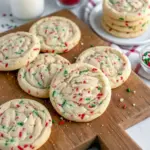 Top-down of a stack of golden sugar cookies studded with colorful sprinkles, showing crisp edges and a chewy center on a festive plate, Christmas Baking Recipes.