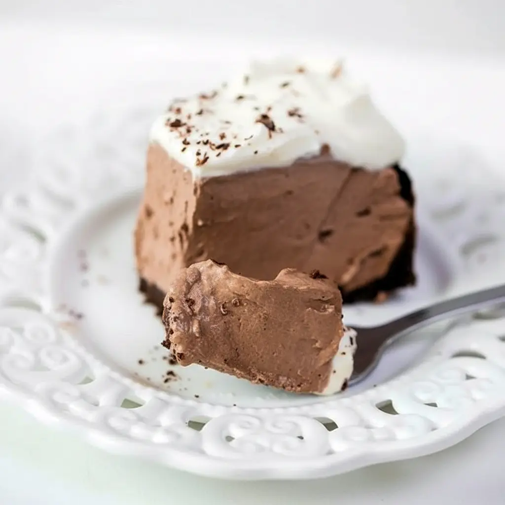 Dessert Parfait-style shot of a glossy chocolate pie slice topped with whipped cream and shavings, a tempting example of Keto Friendly Desserts and Low Carb Sweets, Low Carb Dessert.