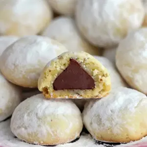 Close-up of powdered shortbread balls hugging a chocolate center — great for Cupcake Cookies Decorated Ideas, a simple Secret Kiss Cookie Recipe, a visual guide on How To Make Secret Kiss Cookies, and a tasty example of Hershey Kisses Cookies, Christmas Cookies With Hershey Kisses.