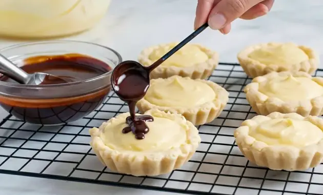 Tray of Boston Cream Pie Cookies: golden cookie cups filled with creamy custard and topped with shiny chocolate ganache — a dreamy example of The Best Cookie Recipes Ever with decadent Cookie Fillings.
