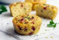 Cottage Cheese Egg Bites Recipe — close-up of golden, baked egg bites in a muffin tin, topped with chopped chives and crispy bacon, ready to serve.