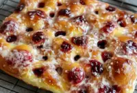 Close-up of a golden, jam-stuffed Focaccia Bread square with glossy fruit filling and a light sugar dusting — a Jam Donut–inspired sweet focaccia ready for brunch.