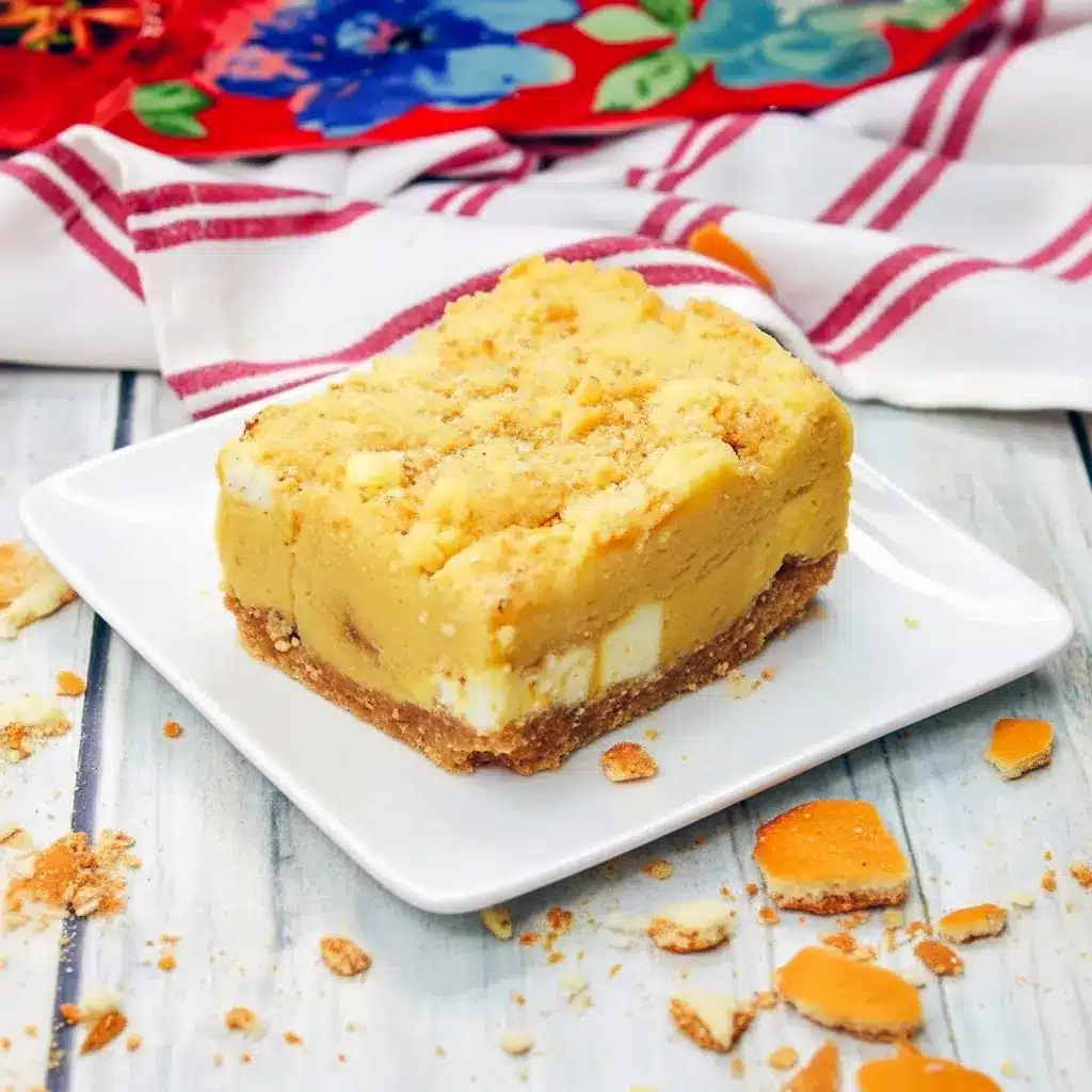 Close-up of a gooey Banana Blondies Recipe square on parchment, showing a golden vanilla-wafer crust, white chocolate pockets, and a fork ready to dig in.