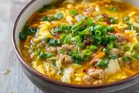 Steaming bowl of egg roll soup with ground pork, shredded cabbage, green onions, and ginger — a simple One Pot Healthy Dinner and an inviting example of Hearty Healthy Soups.