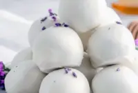 Close-up of glossy white chocolate Chocolate Truffles dusted with dried lavender and a light honey drizzle, arranged on parchment for a delicate spring dessert.