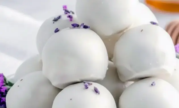 Close-up of glossy white chocolate Chocolate Truffles dusted with dried lavender and a light honey drizzle, arranged on parchment for a delicate spring dessert.