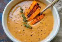 Cozy Soup — bowl of creamy roasted Italian sweet potato soup garnished with thyme and roasted potato wedges, ready to serve.