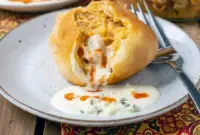 Easy Game Day Dinner Ideas: golden Buffalo Chicken Bombs on a platter, brushed with butter and served with blue cheese dressing and celery sticks.