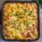 Best Dinner Side Dishes — close-up of honey-glazed corn casserole with a golden-brown top, drizzled honey and parsley garnish in a white baking dish.