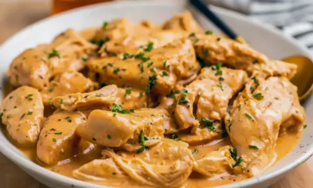 Close-up of shredded Crockpot Honey Mustard Chicken glazed in a golden honey-mustard sauce, garnished with parsley — a perfect example of Mustard Chicken Slow Cooker comfort food.