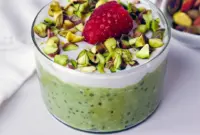 Jar of Raspberry Pistachio Overnight Oats layered with dairy-free yogurt, fresh raspberries, and chopped pistachios — a portable Overnight Oats Plant Based breakfast.