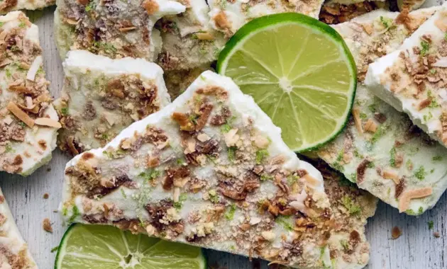 Protein Summer Recipes — frozen key lime yogurt bark pieces on parchment, topped with crushed graham crackers and toasted coconut, ready to grab from the freezer.