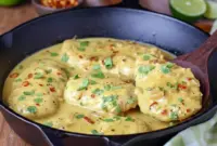 Skillet of Creamy Coconut Lime Chicken over jasmine rice, garnished with chopped cilantro and a lime wedge.