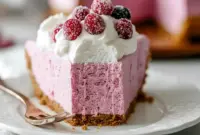 Cranberry Mousse Pie slice on a white plate, topped with whipped cream, sugared cranberries, and a rosemary sprig.