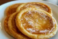 Creme Brule Cookies on a platter, caramelized golden tops cracked to reveal a tender, creamy center, styled with a sprinkle of coarse sugar.