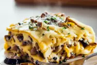 Slice of Mushroom Lasagna With Parmesan Bechamel showing creamy Mushroom Bechamel Lasagna layers, golden cheese, and a sprinkle of grated Pecorino on top.