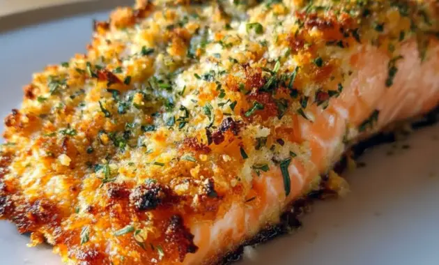 Parmesan-Crusted Salmon on a plate with lemon wedges and greens — golden crust and flaky fish, a classic Salmon Dinner Idea.