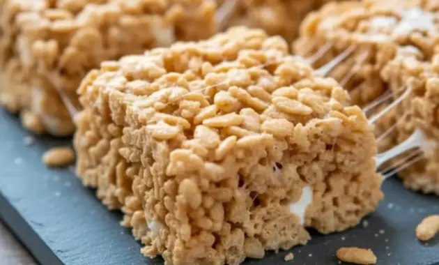 Close-up of two stacked Churro Rice Krispie bars, golden with cinnamon-sugar coating and gooey marshmallow pulls.