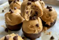 Greek Yogurt And Peanut Butter frozen bites on a small plate, dotted with mini chocolate chips — perfect Greek Yogurt Bites for a healthy snack.