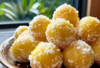 A platter of Pineapple Christmas Balls rolled in shredded coconut and arranged with festive greenery — a colorful Pineapple Recipes holiday treat ready to serve.