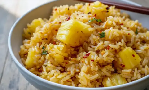 Pineapple Rice — close-up of coconut-scented rice studded with pineapple chunks, grated ginger, and green onions, served with a lime wedge.
