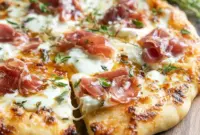 Home Pizza Ideas close-up of a white pizza with ricotta, melted mozzarella, beef prosciutto, and hot honey drizzle — a tasty example of Pizza Recipes Toppings and Fancy Pizza Toppings.