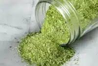 Jar of green-speckled Jalapeno Salt Recipe with fresh jalapeños and a lime wedge — a simple example of Infused Salt Recipes.