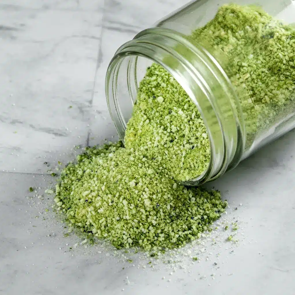 Jar of green-speckled Jalapeno Salt Recipe with fresh jalapeños and a lime wedge — a simple example of Infused Salt Recipes.