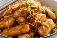 Close-up of golden pan-seared halibut glazed with soy-ginger sauce, topped with crispy ginger strips and scallions — an Asian Fish Dish Recipe and easy Asian Fish Dishes weeknight meal.