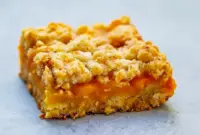 Mango Oatmeal Bars — golden oat crumble bars with bright mango filling stacked on a wire rack, ready to serve.