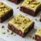 Close-up slice of Pistachio Brownies showing a glossy pistachio ganache, chopped pistachios, and a crackly brownie top.