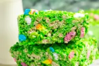 Close-up of a green Lucky Charms Rice Krispie square with marshmallow bits and a glossy finish — St Pats Day Snacks and St Patrick Day Treats styled on a festive platter.