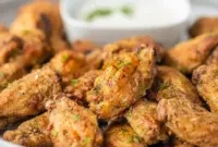 Close-up of crispy Dill Pickle Chicken Wings glazed with dill and served with a bowl of creamy Pickle Wing Sauce — a tangy Pickle Juice Wings favorite.