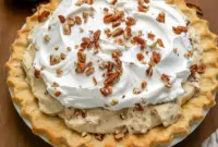 Slice of Pecan Cream Pie with whipped cream and toasted pecans on a plate — creamy filling and crunchy topping, a classic Pies With Cream Cheese dessert.