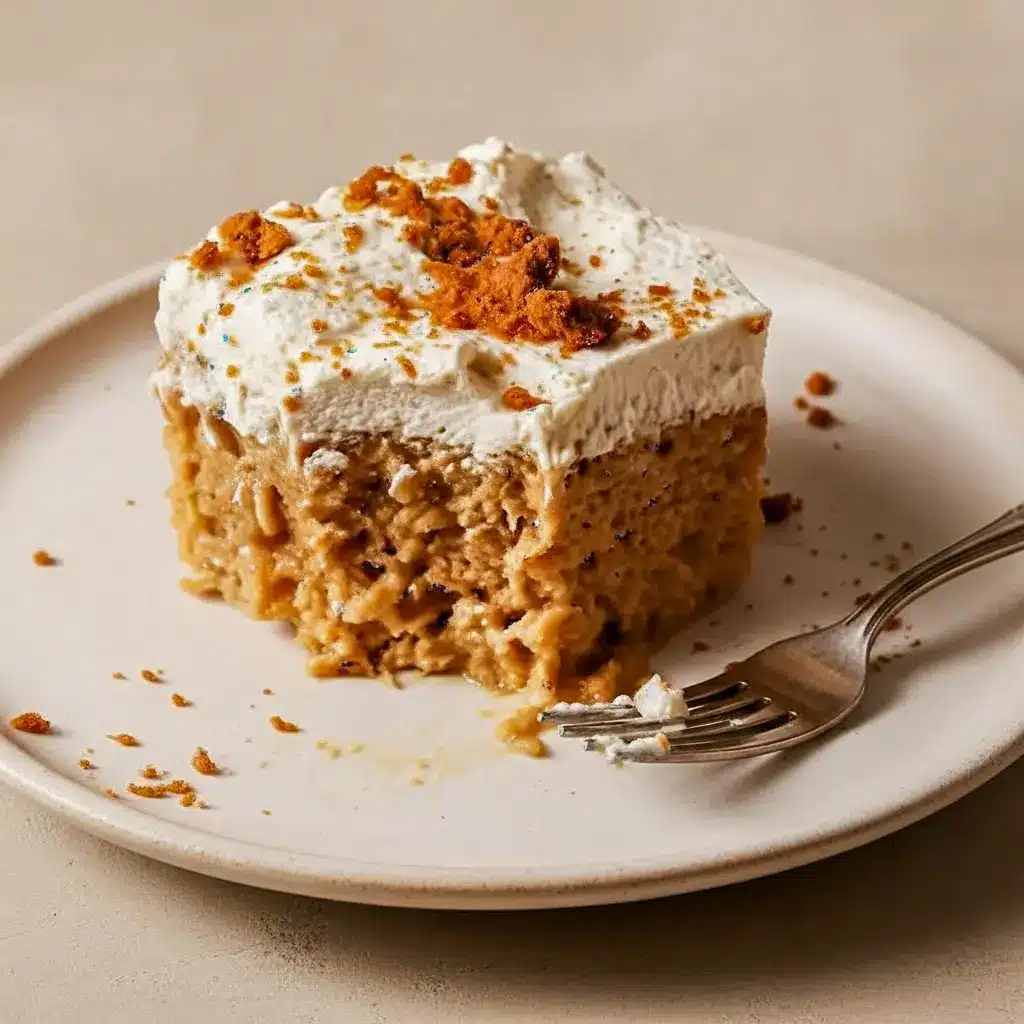 Homemade Tres Leches Cake slice on a plate, topped with cookie-butter whipped cream and crushed Biscoff crumbs.