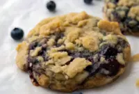 Thick Blueberry Muffin Cookies with golden streusel, jam pockets, and plump blueberries on parchment — close-up of a chewy, bakery-style cookie.